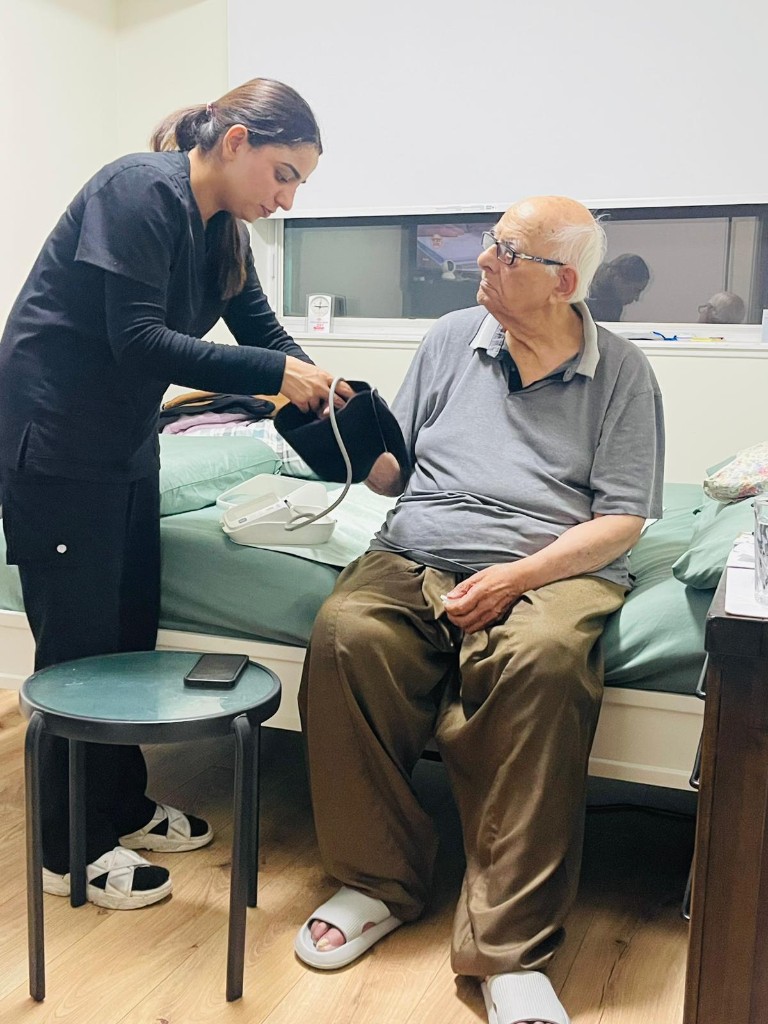 Caregiver checking an elder’s blood pressure